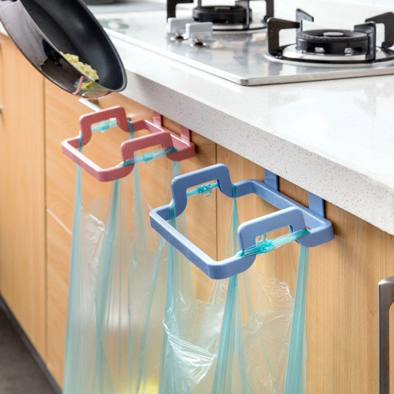 White plastic hanging garbage bag holder mounted over a kitchen cabinet door