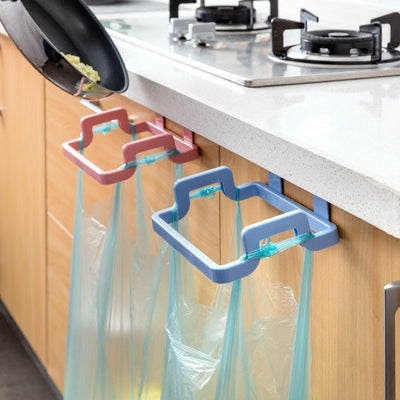 White plastic hanging garbage bag holder mounted over a kitchen cabinet door