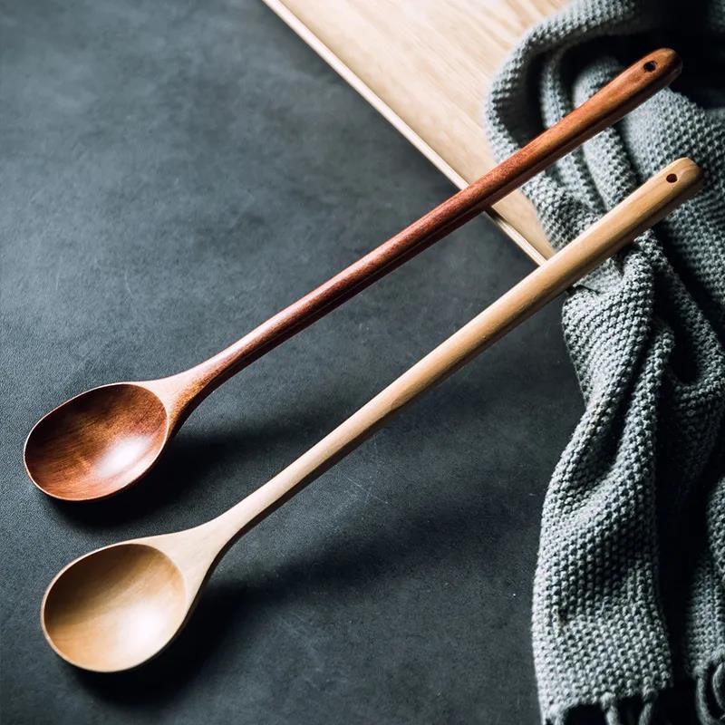 Long handle stirring cooking spoon resting against a tall stainless steel stockpot
