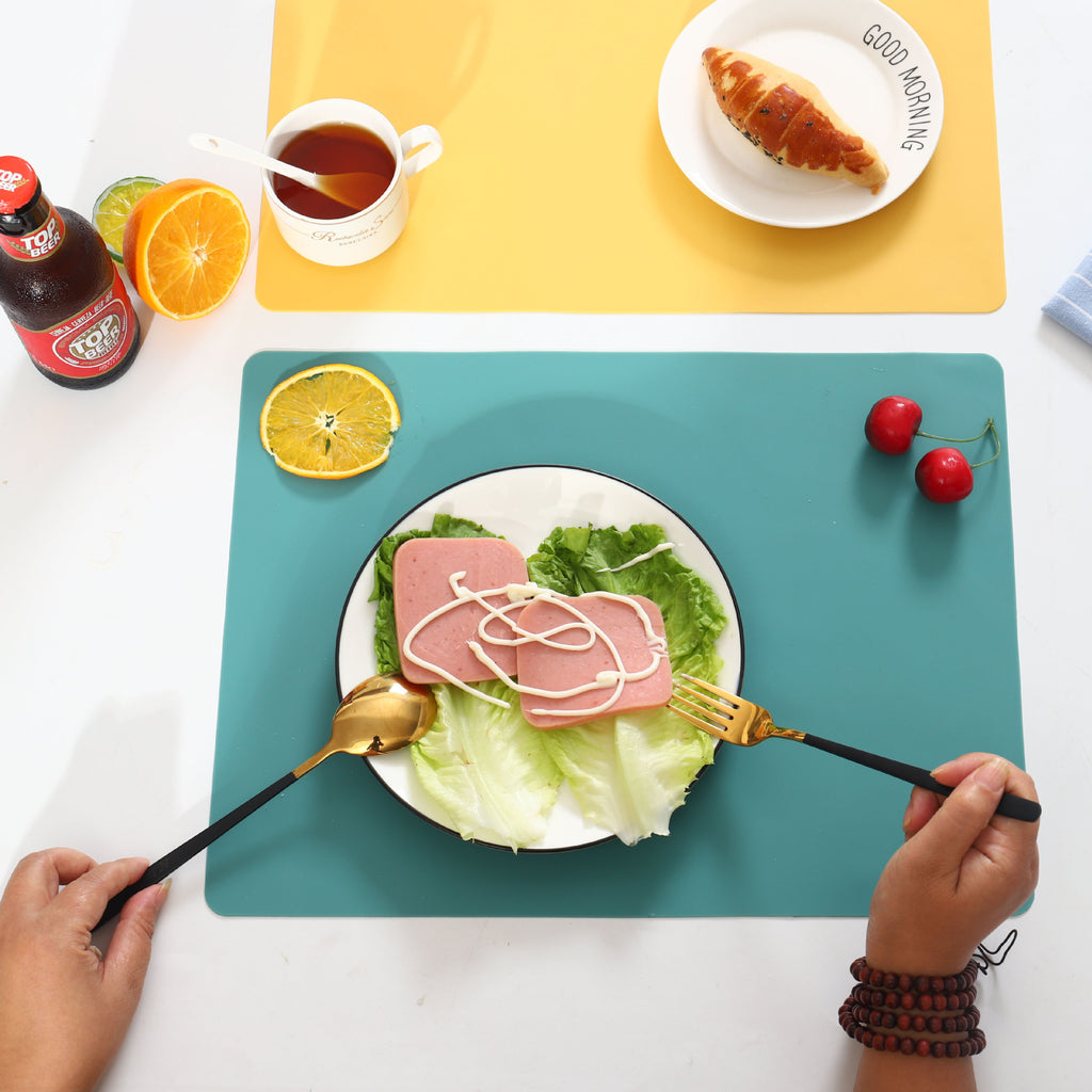 Grey non-slip silicone table placemat placed under a plate on a wooden dining table