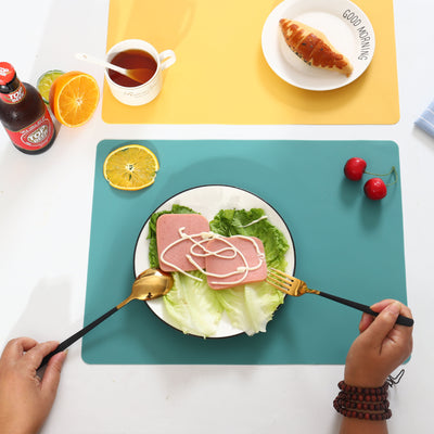 Grey non-slip silicone table placemat placed under a plate on a wooden dining table