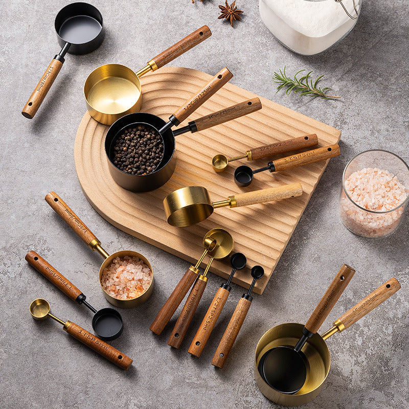 8 piece stainless steel measuring cups and spoons with wooden walnut handles arranged on a wooden countertop