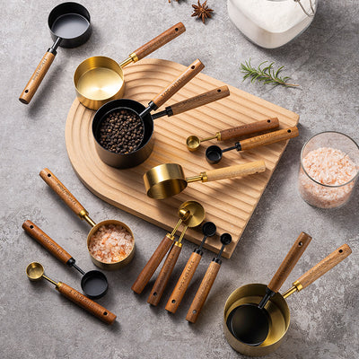 8 piece stainless steel measuring cups and spoons with wooden walnut handles arranged on a wooden countertop
